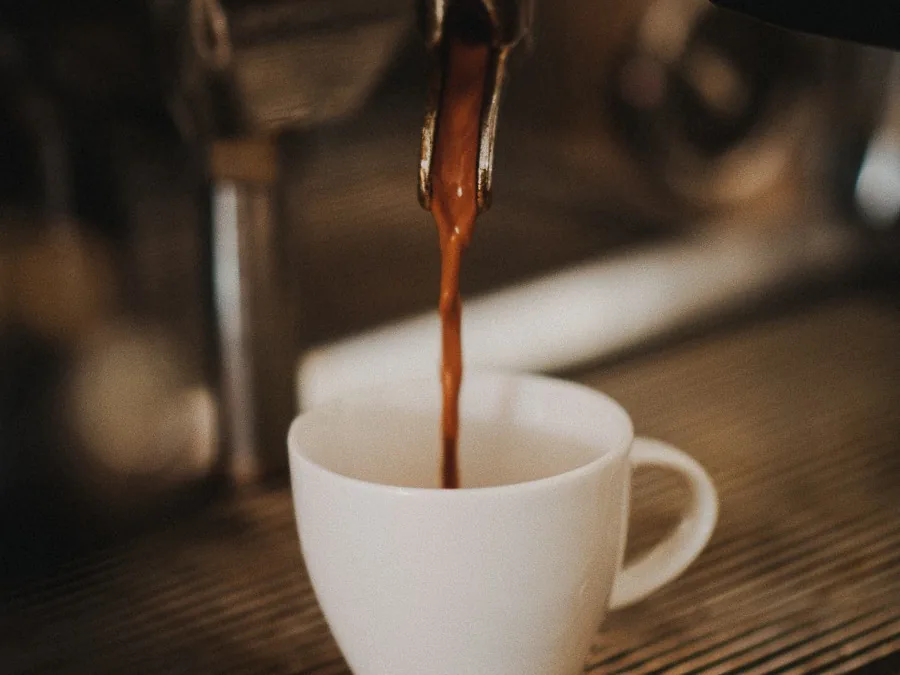 Espresso läuft aus dem Siebträger in eine weiße Tasse